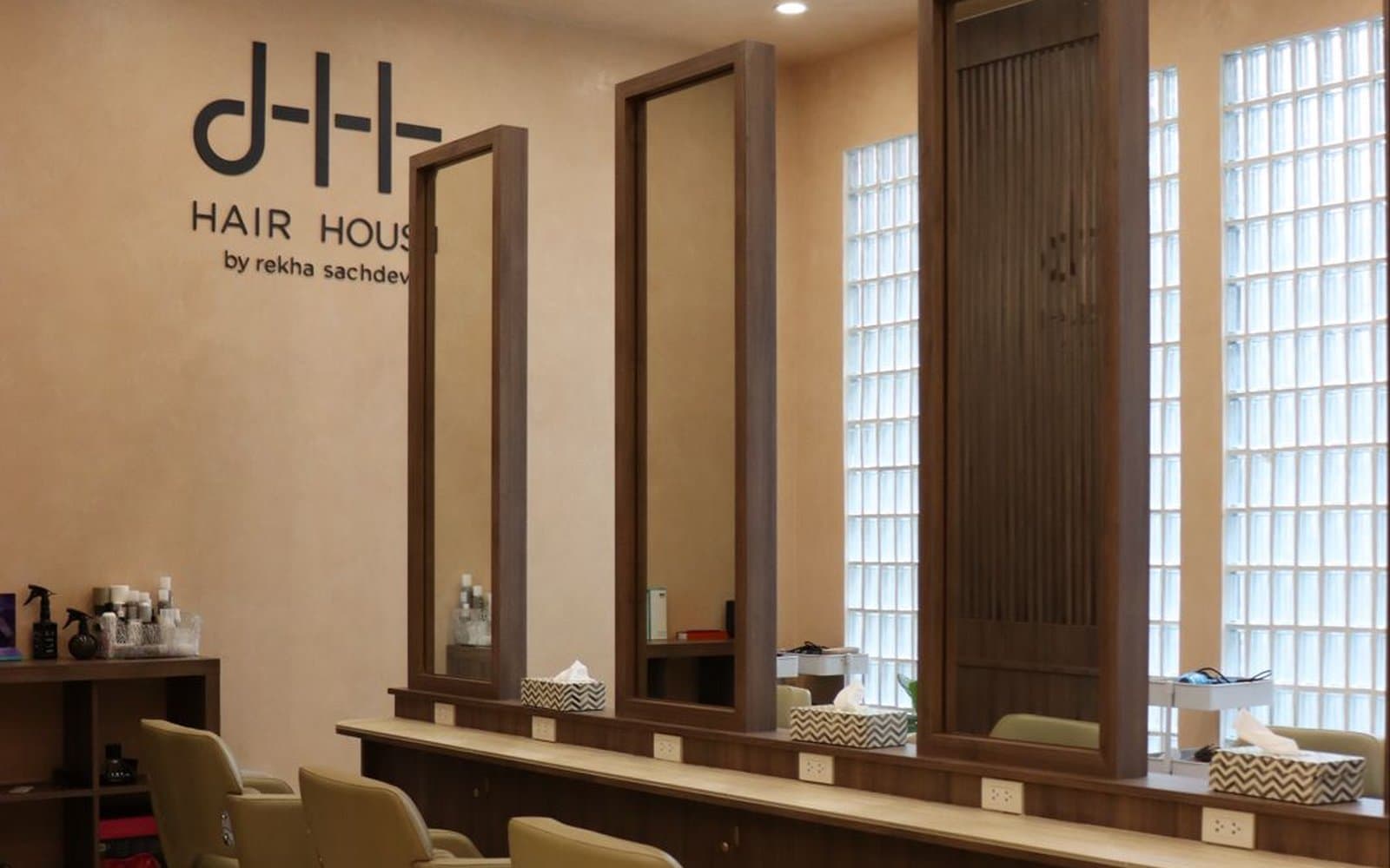 Styling stations with mirrors and sage chairs under the HAIR HOUSE by rekha sachdev wall logo, Bangkok