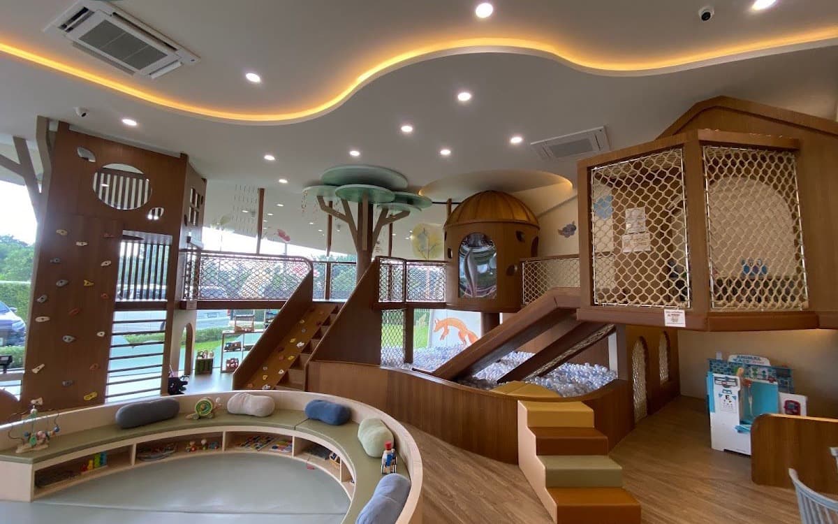 The wooden indoor playground at Little Owly’s with a treehouse, ball pit slide, and climbing wall