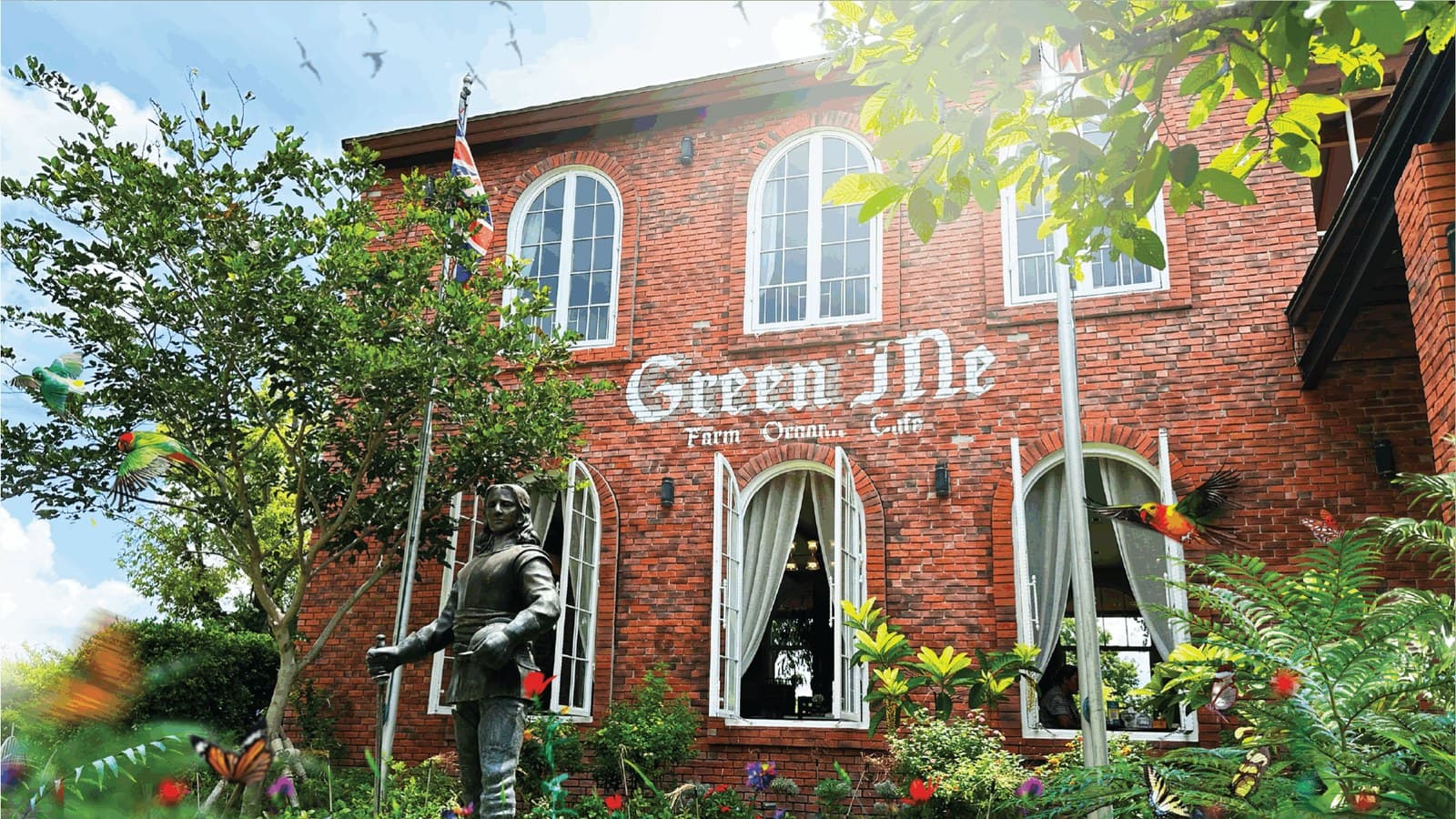 The red brick farmhouse cafe at Green Me Organic Farm in Khao Yai, with arched white windows and a flower garden out front
