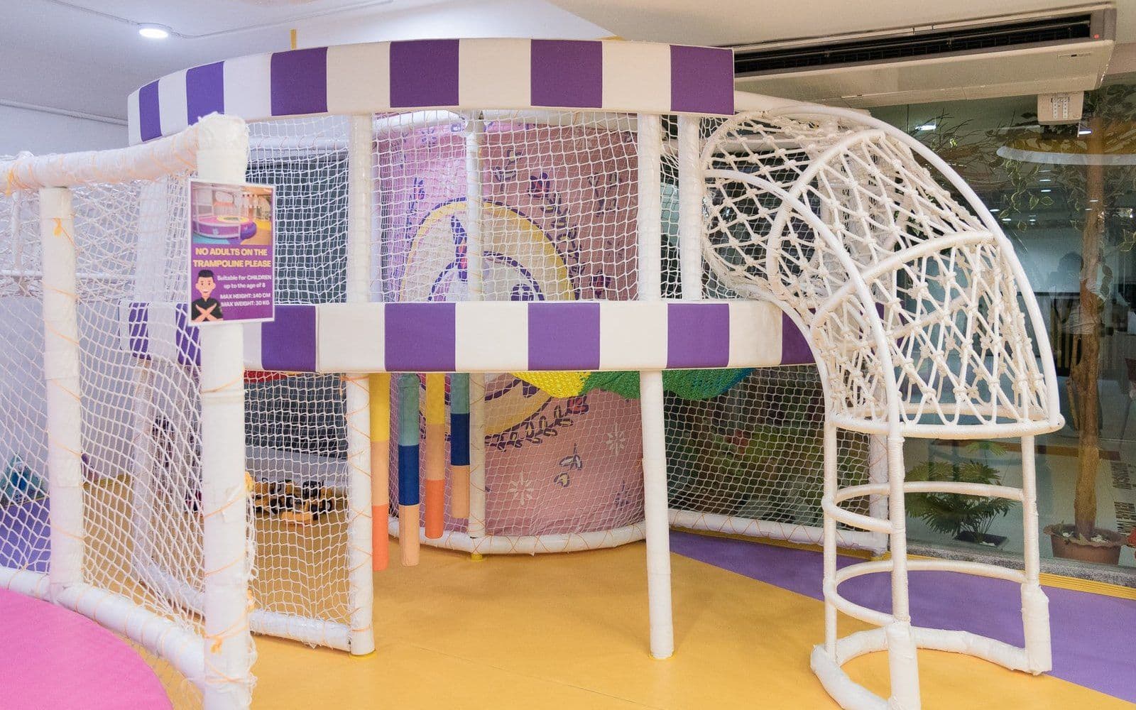 The colorful indoor play structure with slides, climbing nets, and a trampoline at Sparkles & Sprinkles Kids Cafe, Bangkok